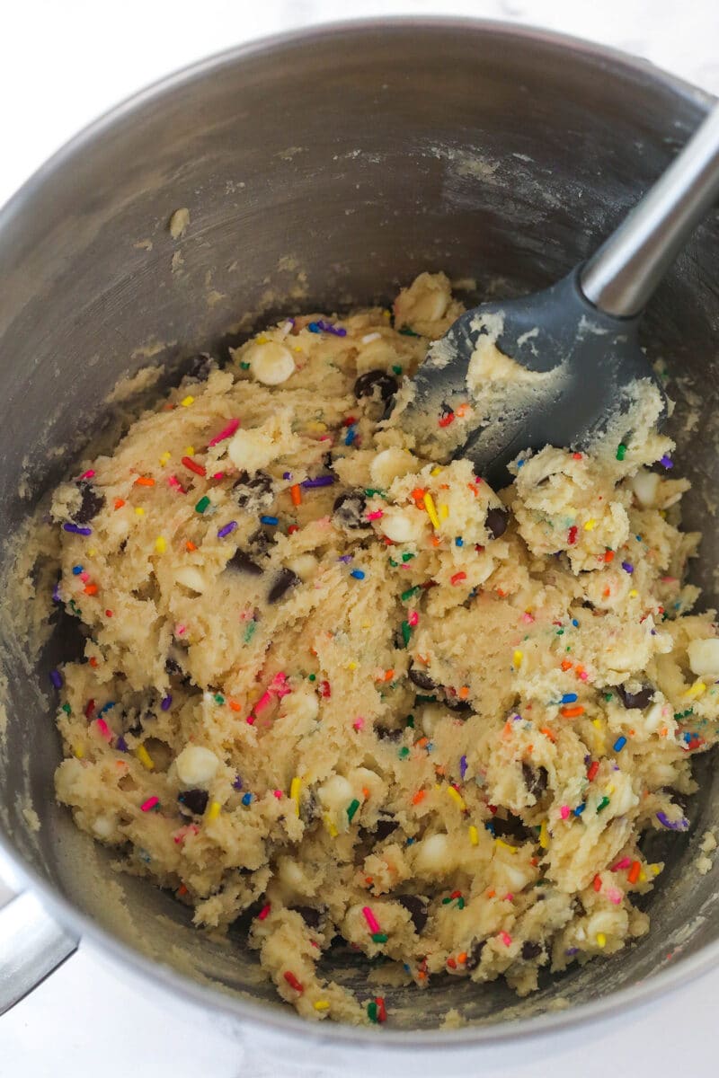 Cookie dough after adding dry ingredients, sprinkles, chocolate chips, and white chocolate chips into cookie cake batter.