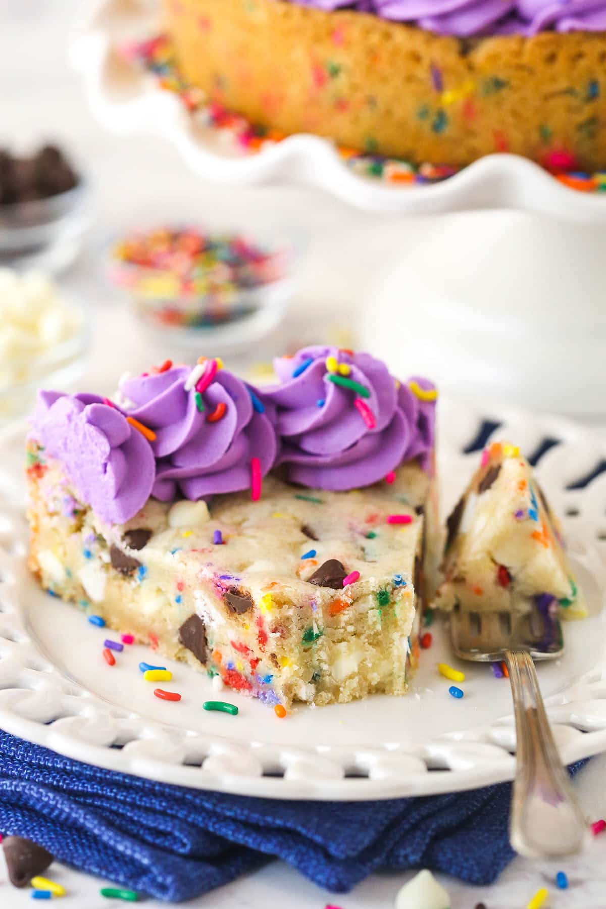 A slice of Funfetti cookie cake with a bite taken out of it.