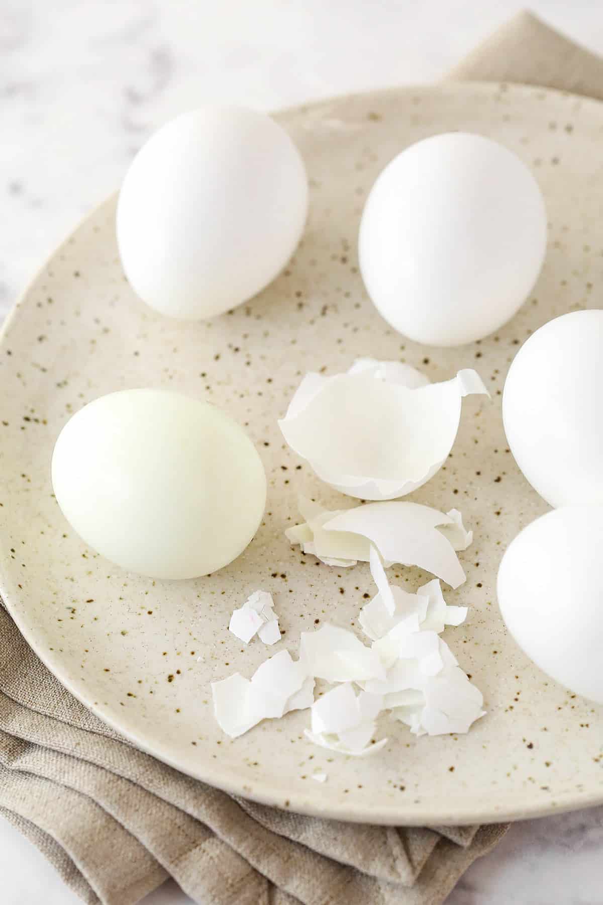 Hard boiled eggs on a plate. One is pealed.