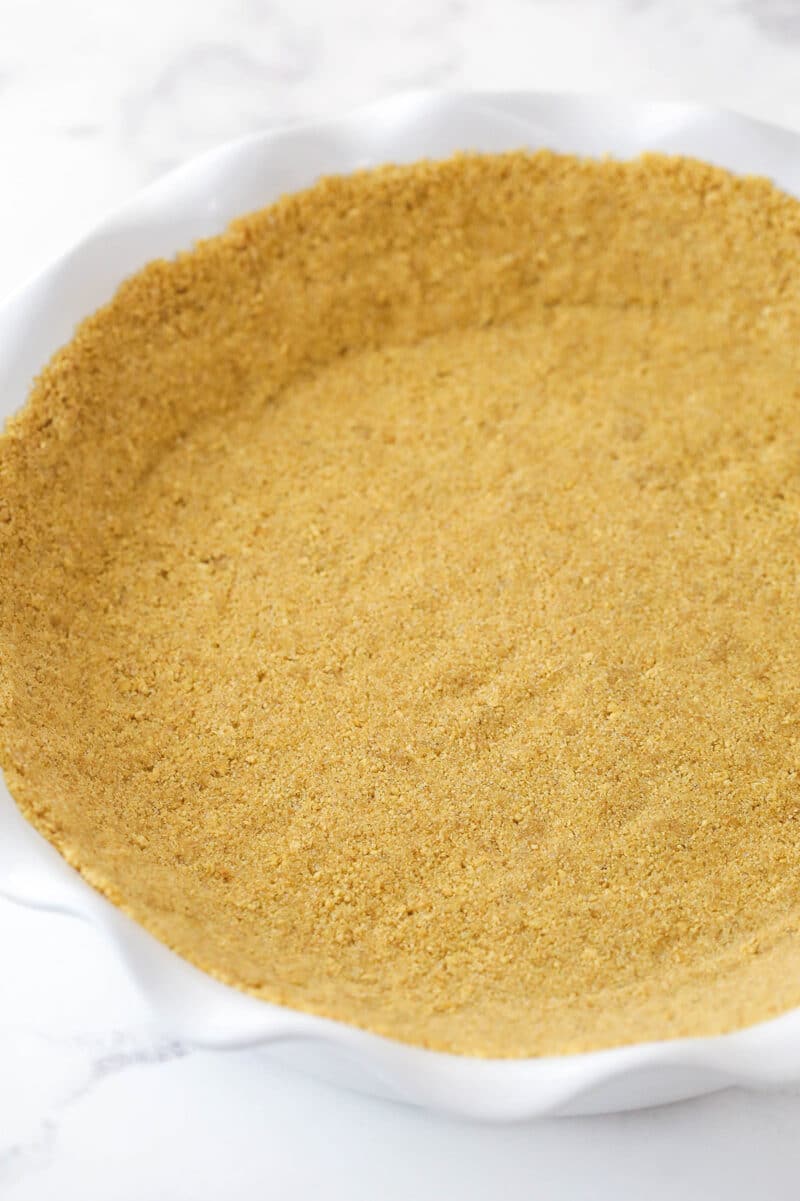 Pressing graham cracker crust into the bottom and up the sides of a pie dish.