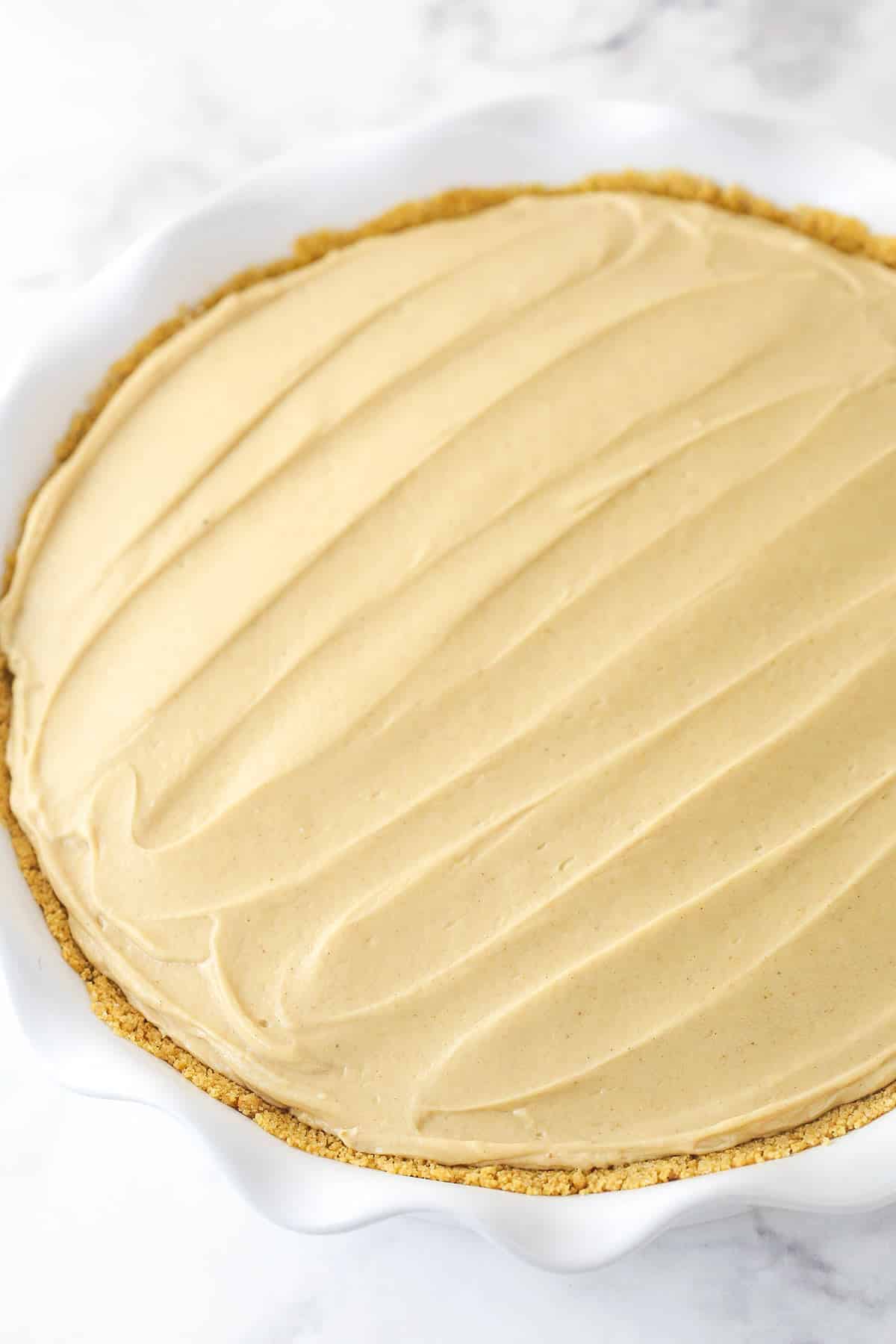 Spreading a light and creamy peanut butter filling into a graham cracker pie crust.