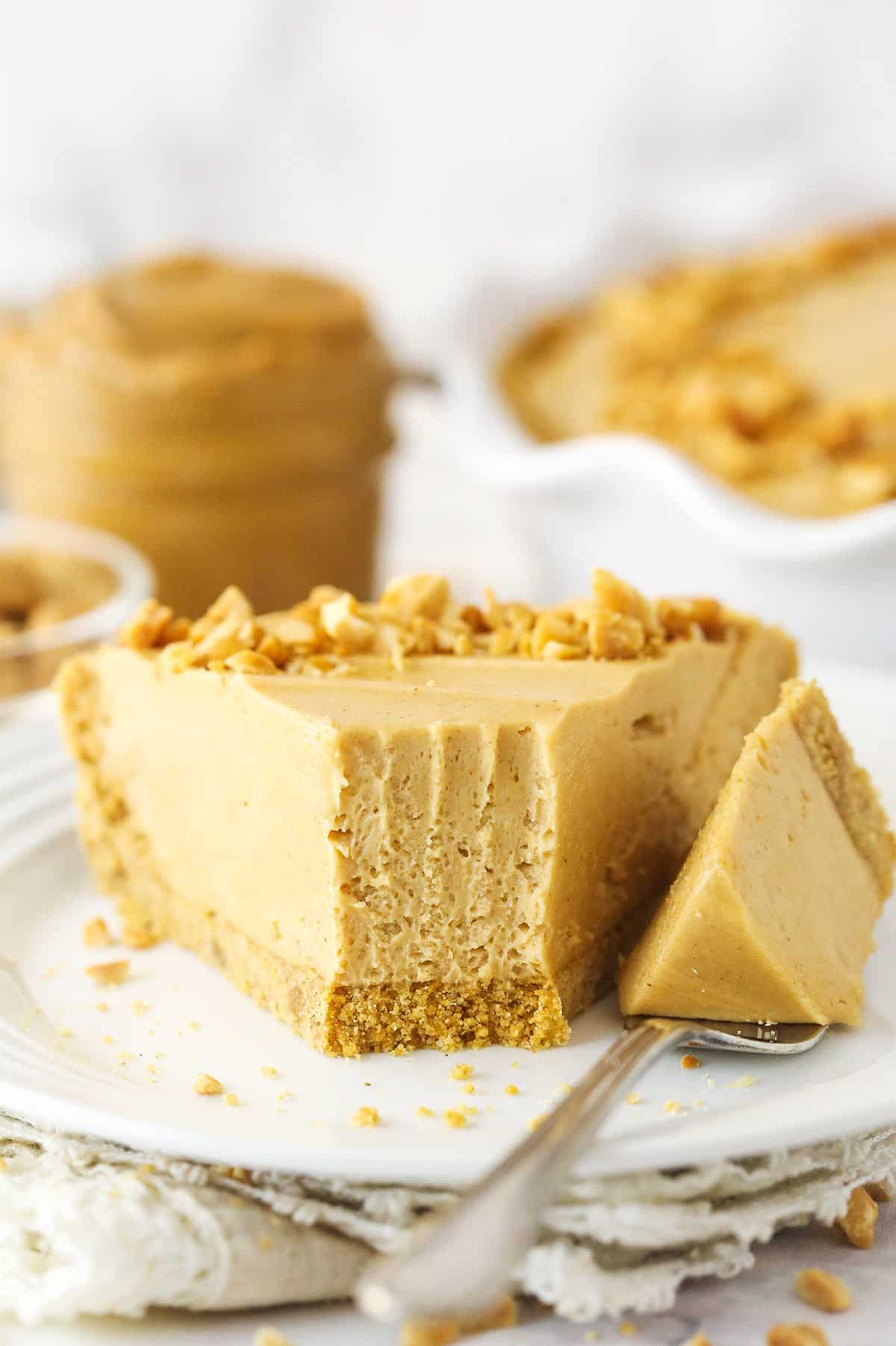 A slice of peanut butter pie on a plate with a fork taking a bite out of it.