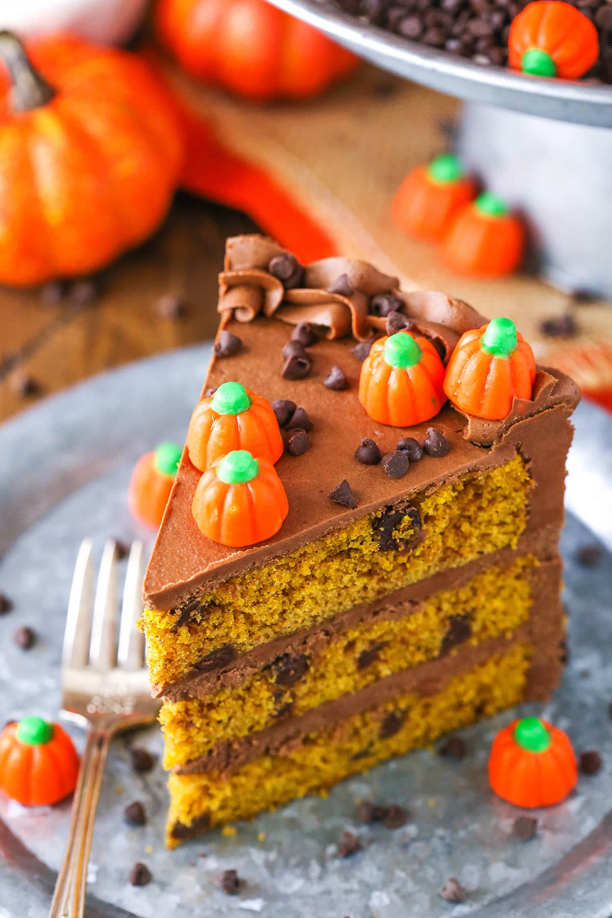 A slice of Pumpkin Chocolate Chip Layer Cake next to a fork on a gray plate