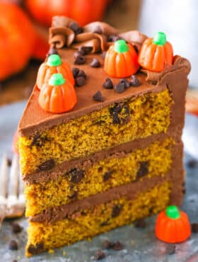 A slice of Pumpkin Chocolate Chip Layer Cake next to a fork on a gray plate
