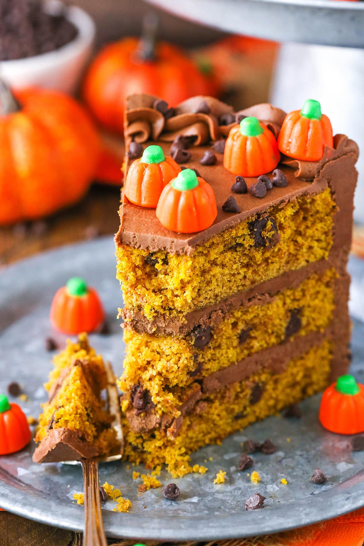 A slice of Pumpkin Chocolate Chip Layer Cake with a bite removed next to a fork on a gray plate