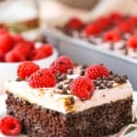 A square serving of Raspberry Chambord Chocolate Poke Cake next to a silver fork on a white plate