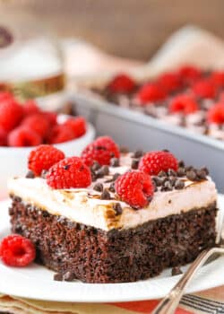 A square serving of Raspberry Chambord Chocolate Poke Cake next to a silver fork on a white plate