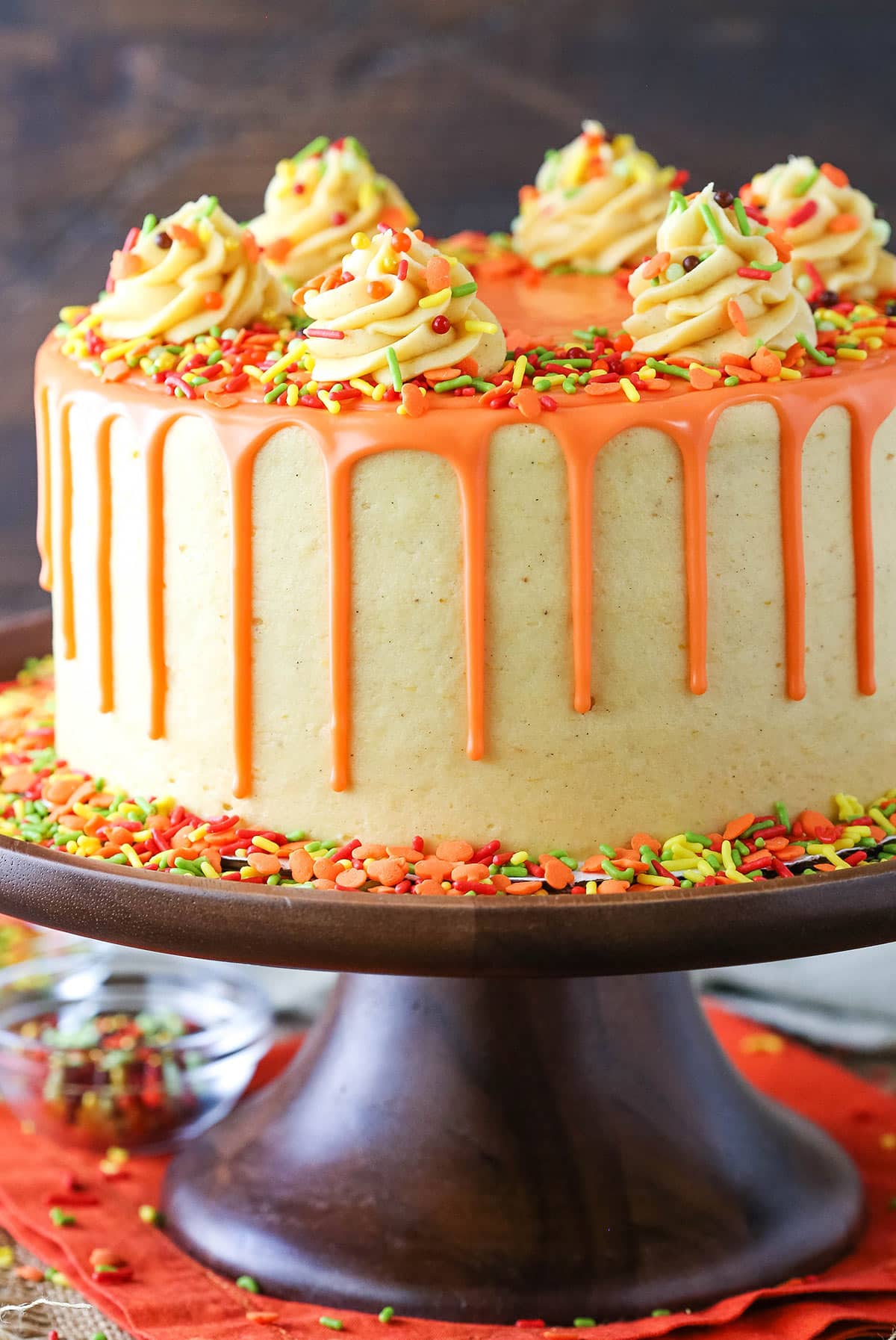 Side view of a full Spice Cake with Pumpkin Mascarpone Buttercream on a dark brown cake stand