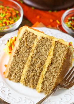 A slice of Spice Cake with Pumpkin Mascarpone Buttercream next to a fork on a white plate