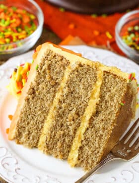 A slice of Spice Cake with Pumpkin Mascarpone Buttercream next to a fork on a white plate