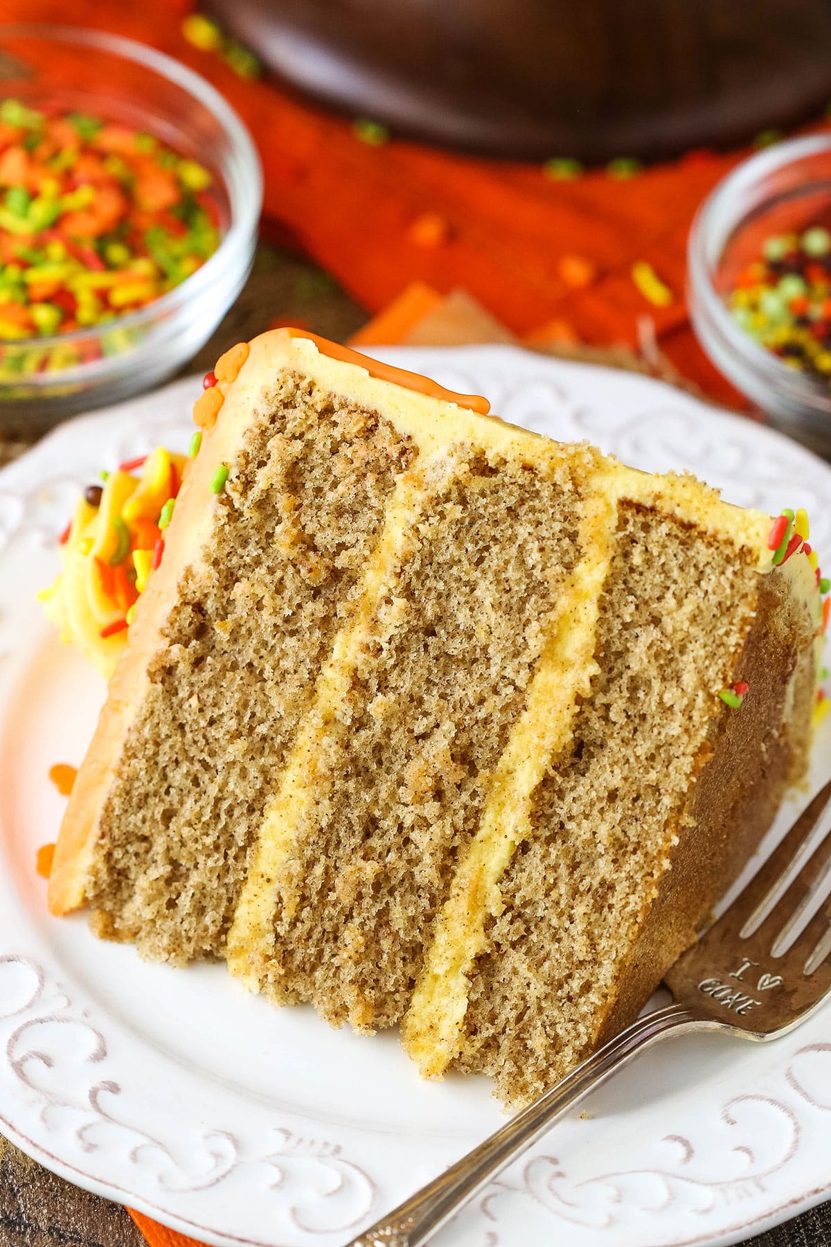 A slice of Spice Cake with Pumpkin Mascarpone Buttercream next to a fork on a white plate