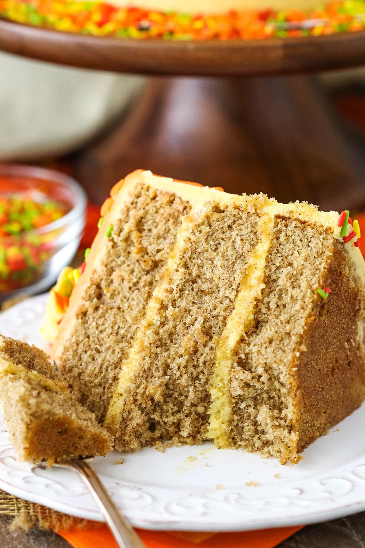 A slice of Spice Cake with Pumpkin Mascarpone Buttercream with a bite missing on a white plate