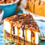 A slice of Turtle Cheesecake next to a fork on a blue plate