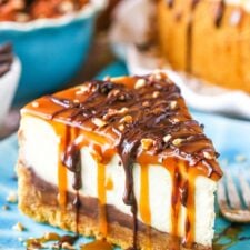 A slice of Turtle Cheesecake next to a fork on a blue plate