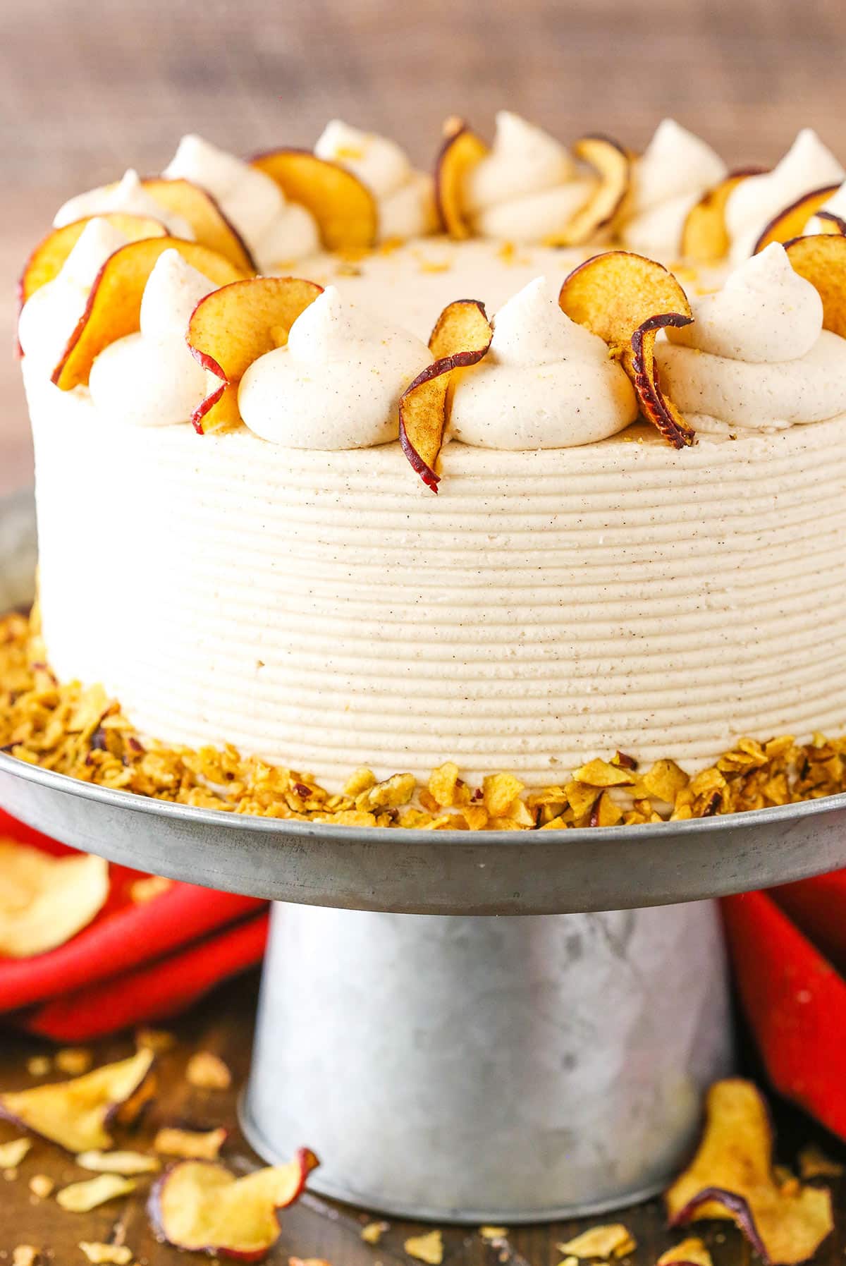 This Cinnamon Apple Layer Cake is incredibly moist, made with fresh apples and has the most amazing apple filling! It's the perfect fall cake! Side view of a full Cinnamon Apple Layer Cake on a gray cake stand