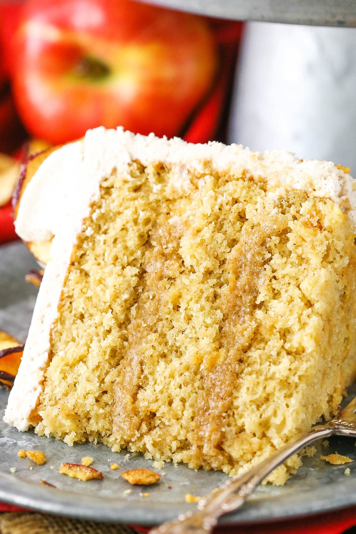 A slice of Cinnamon Apple Layer Cake next to a silver fork on a gray plate