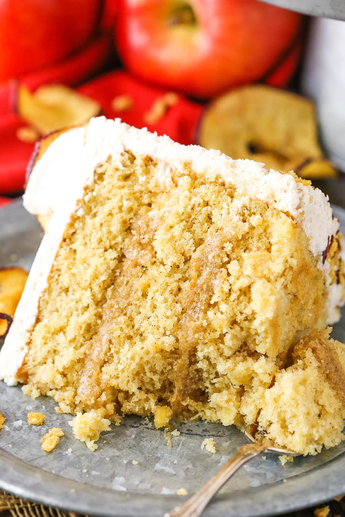 A slice of Cinnamon Apple Layer Cake with a bite removed next to a silver fork on a gray plate