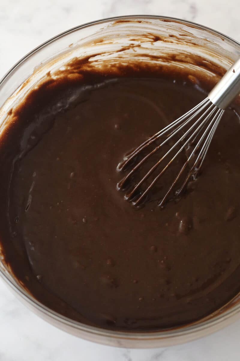 Whisking eggs, milk, and vegetable oil into the dry ingredients for chocolate cake batter.