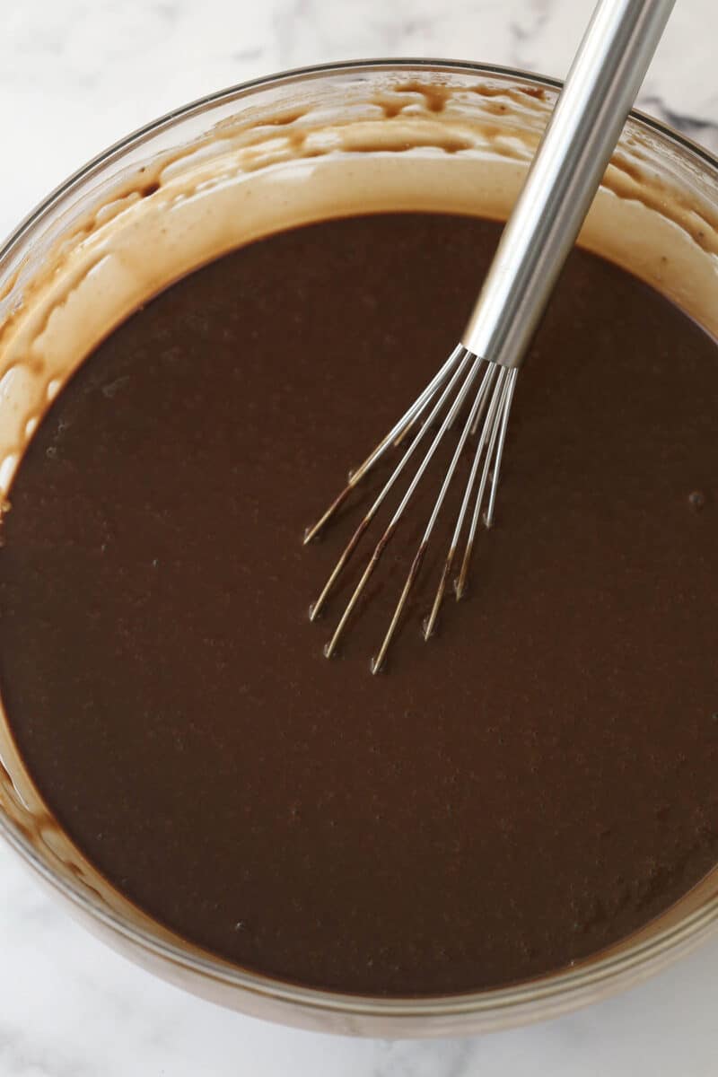 Whisking vanilla and hot water into chocolate cake batter.