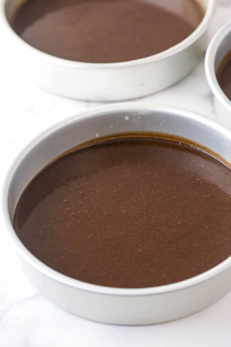 Chocolate cake batter in 3 cake pans.