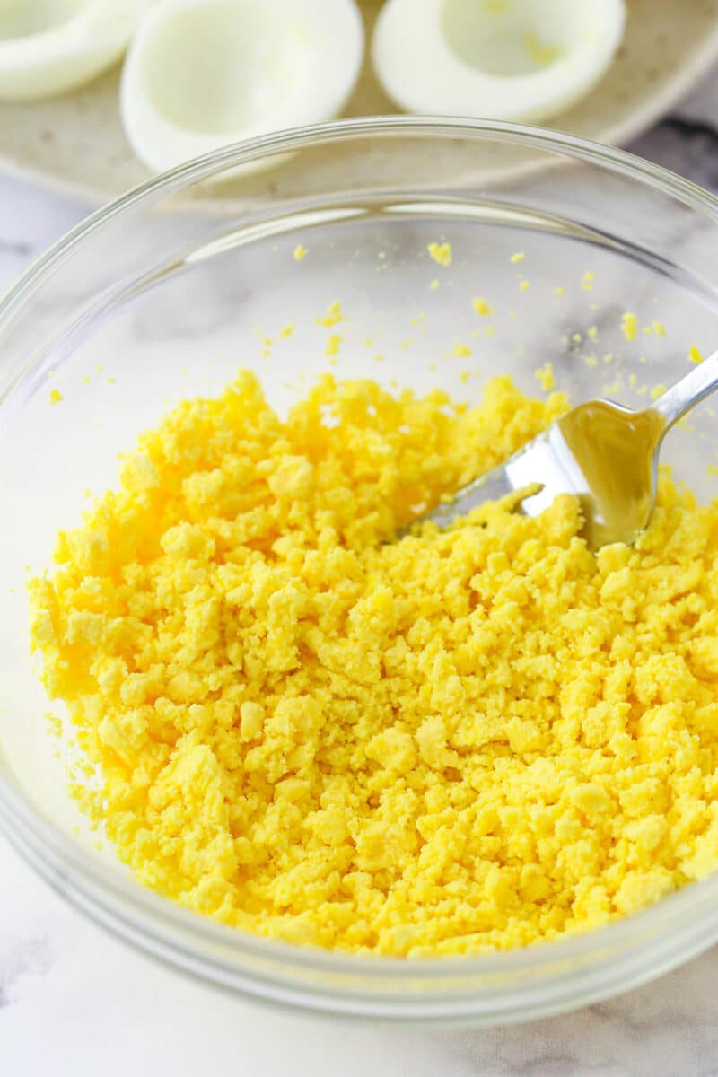 Mashing egg yolks until crumbly.