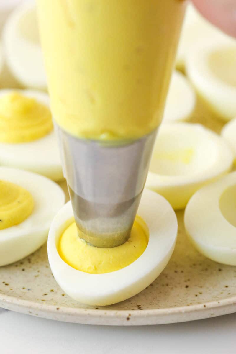 Piping a creamy egg yolk mixture into egg whites.