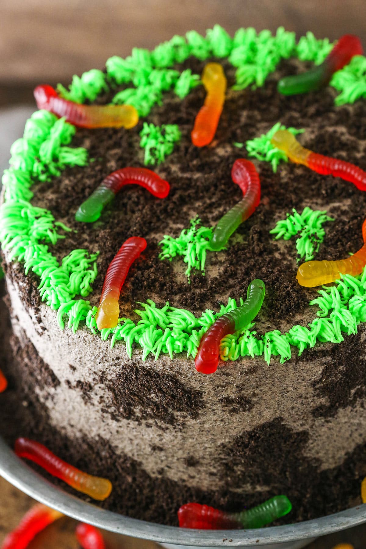 This Dirt Cake is a moist chocolate cake filled with frosting that's loaded with Oreos and layered with more Oreo crumbs! Overhead view of a full Dirt Cake on a gray cake stand