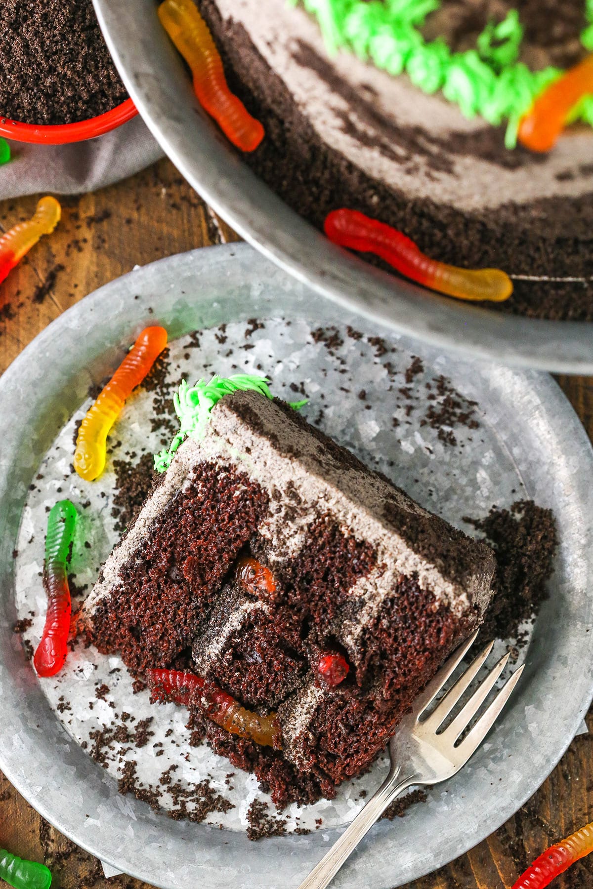 A slice of Dirt Cake next to a silver fork on a gray plate