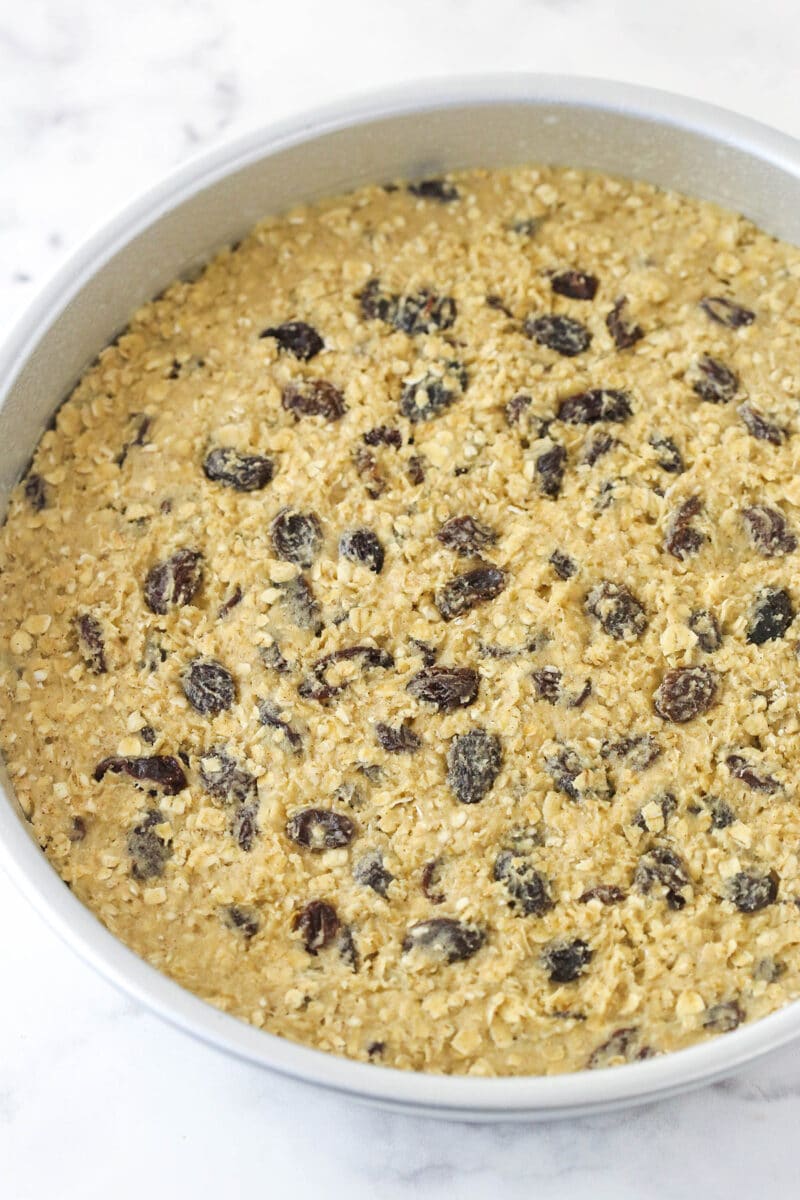 Oatmeal raisin cookie cake is soft and chewy, loaded with warming cinnamon and sweet raisins, and topped with the best maple buttercream. Oatmeal raisin cookie dough pressed into a cake pan.