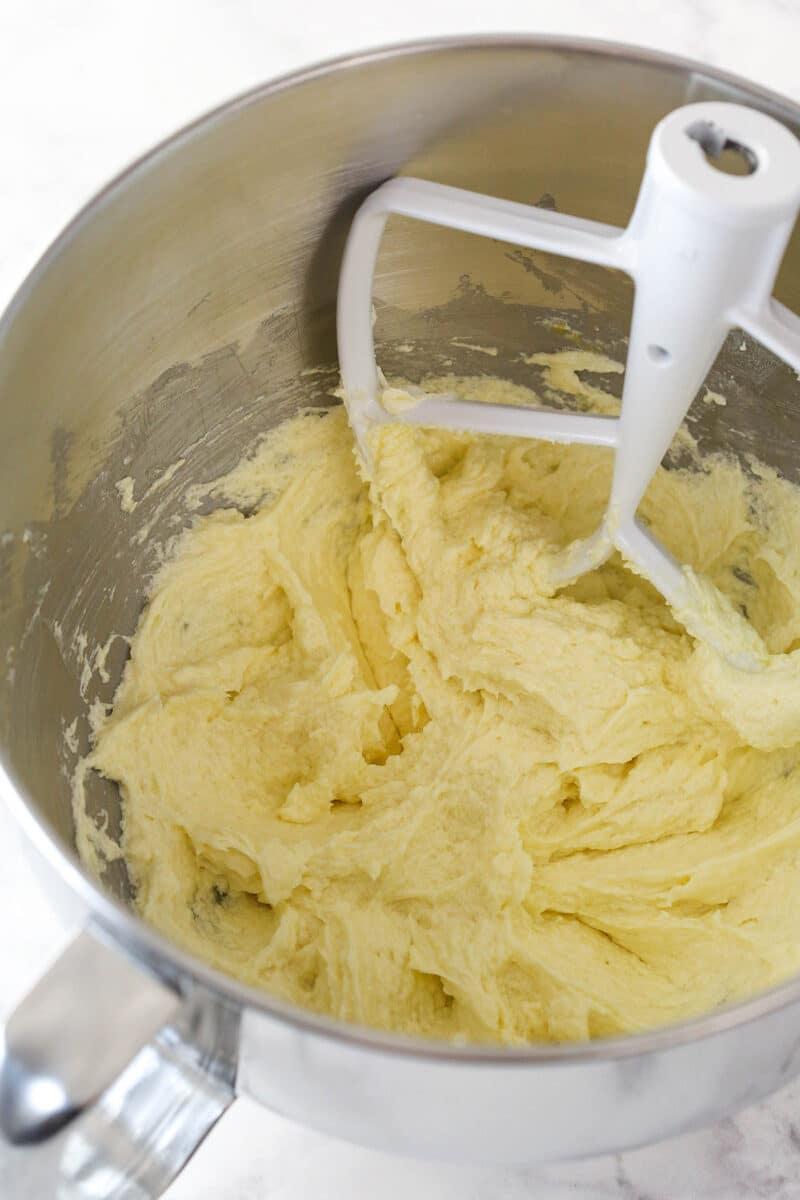 Mixing eggs into creamed butter, sugar, oil, and vanilla.