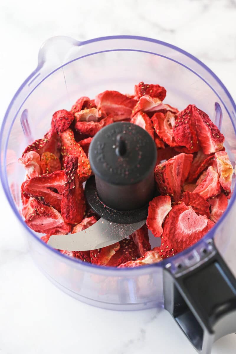 Adding freeze-dried strawberries to a food processor.