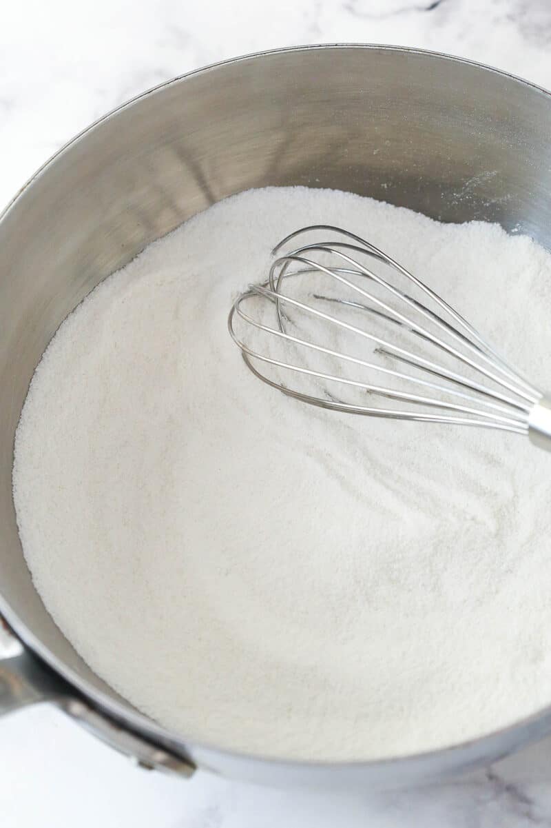 Whisking together sugar, flour, and salt in a saucepan.