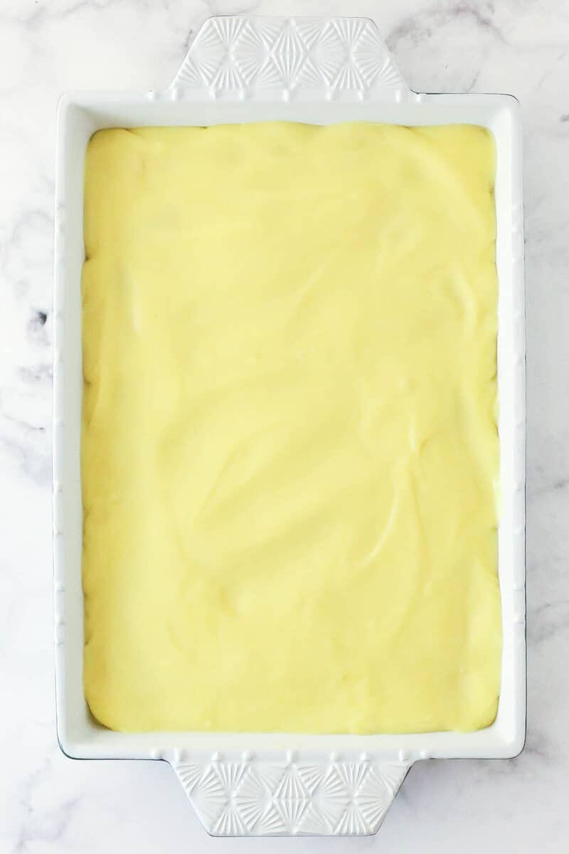 Spreading vanilla pudding over layers of vanilla wafters and banana slices.