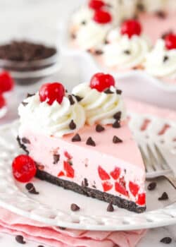 A slice of cherry chocolate ice cream pie on a plate with a fork.