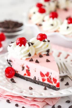 A slice of cherry chocolate ice cream pie on a plate with a fork.