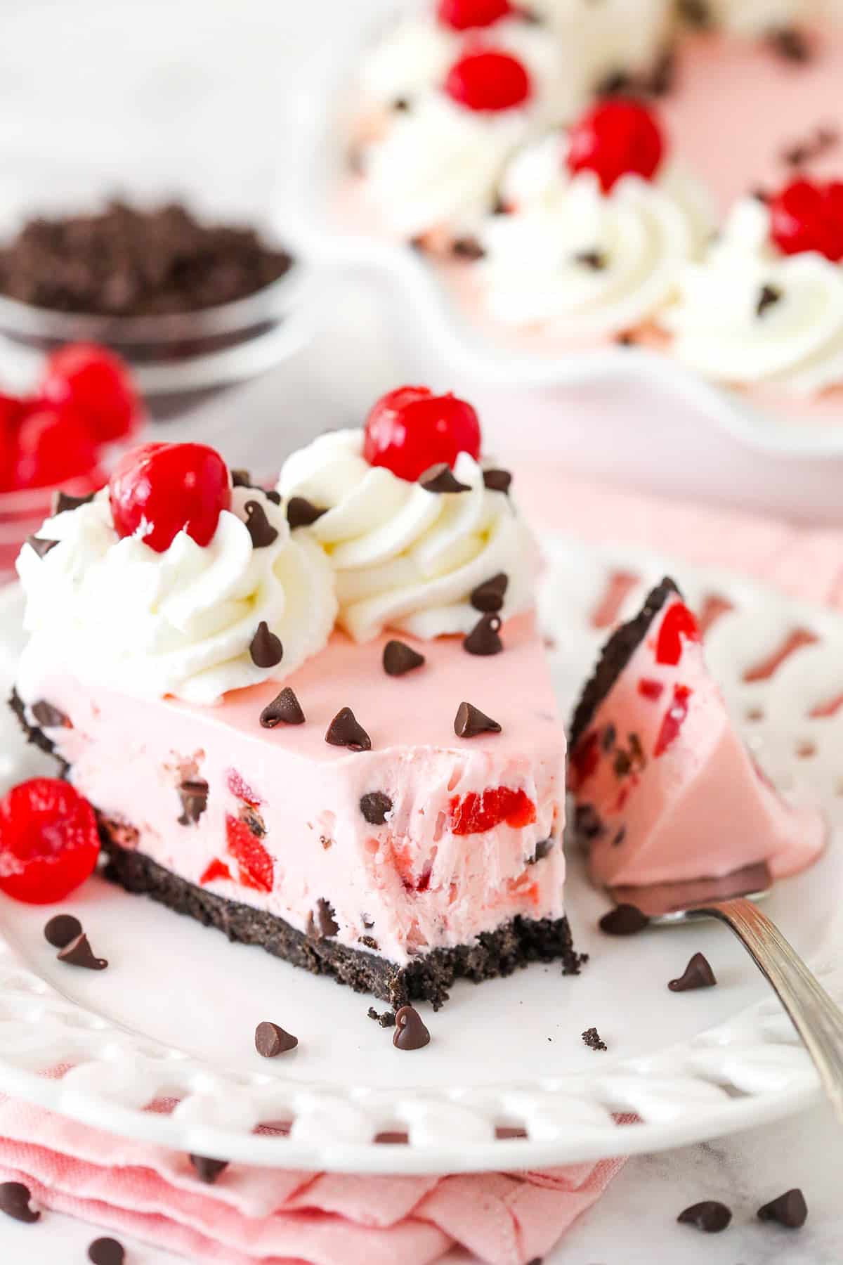 A fork taking a bite out of a slice of cherry chocolate ice cream pie.