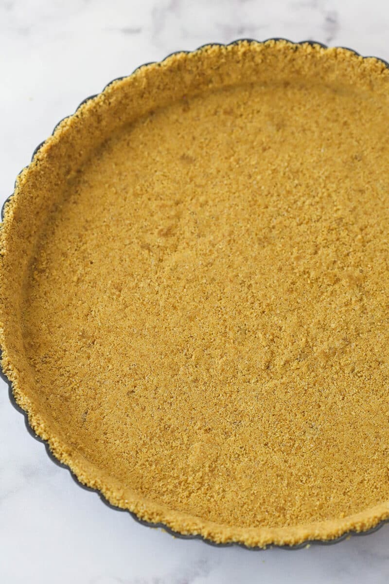 This lemon tart is made up of graham cracker crust, a sweet and tangy, creamy lemon filling, and a fluffy whipped cream topping. Graham cracker crust in a tart pan.
