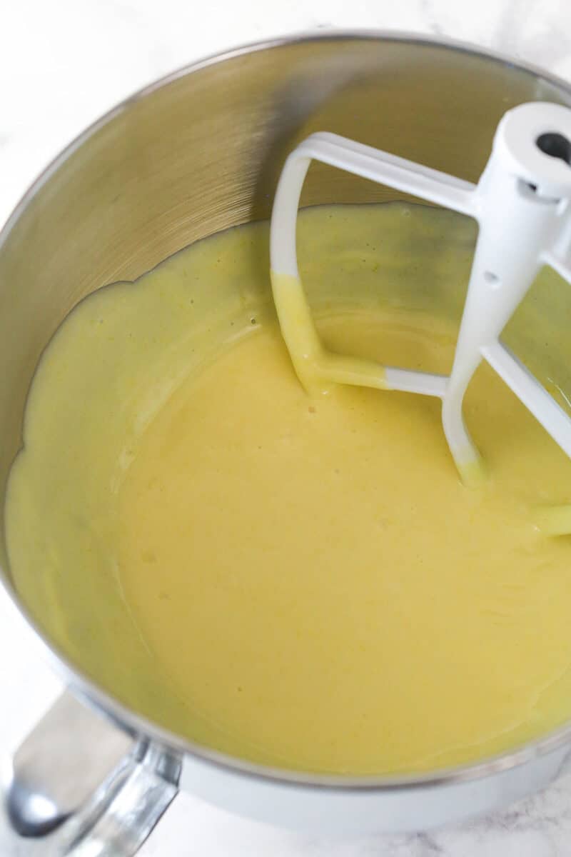 Mixing lemon juice and sweetened condensed milk into egg yolks and lemon zest beaten to light and fluffy.
