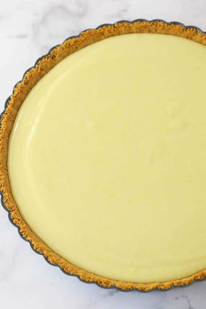 This lemon tart is made up of graham cracker crust, a sweet and tangy, creamy lemon filling, and a fluffy whipped cream topping. Lemon tart batter in a graham cracker crust.