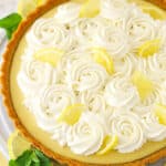 A whole lemon tart surrounded by lemon slices.