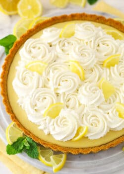 A whole lemon tart surrounded by lemon slices.