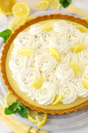 A whole lemon tart surrounded by lemon slices.
