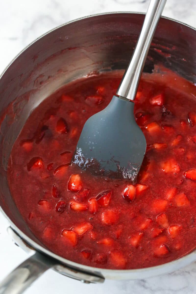 Stirring strawberry topping for mini strawberry cheesecakes.