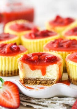 A mini strawberry cheesecake with a bite taken out of it.