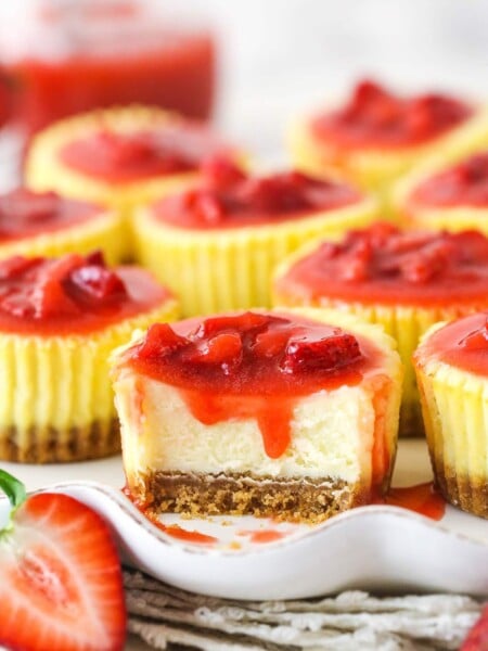 A mini strawberry cheesecake with a bite taken out of it.