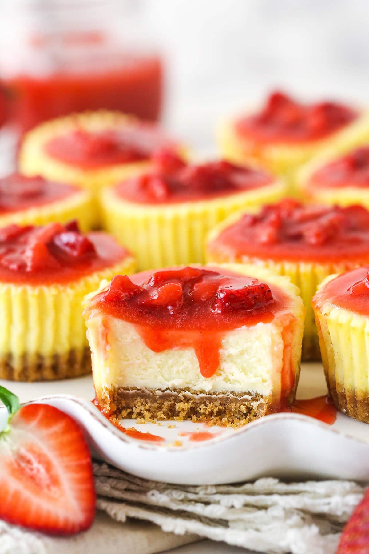A mini strawberry cheesecake with a bite taken out of it.