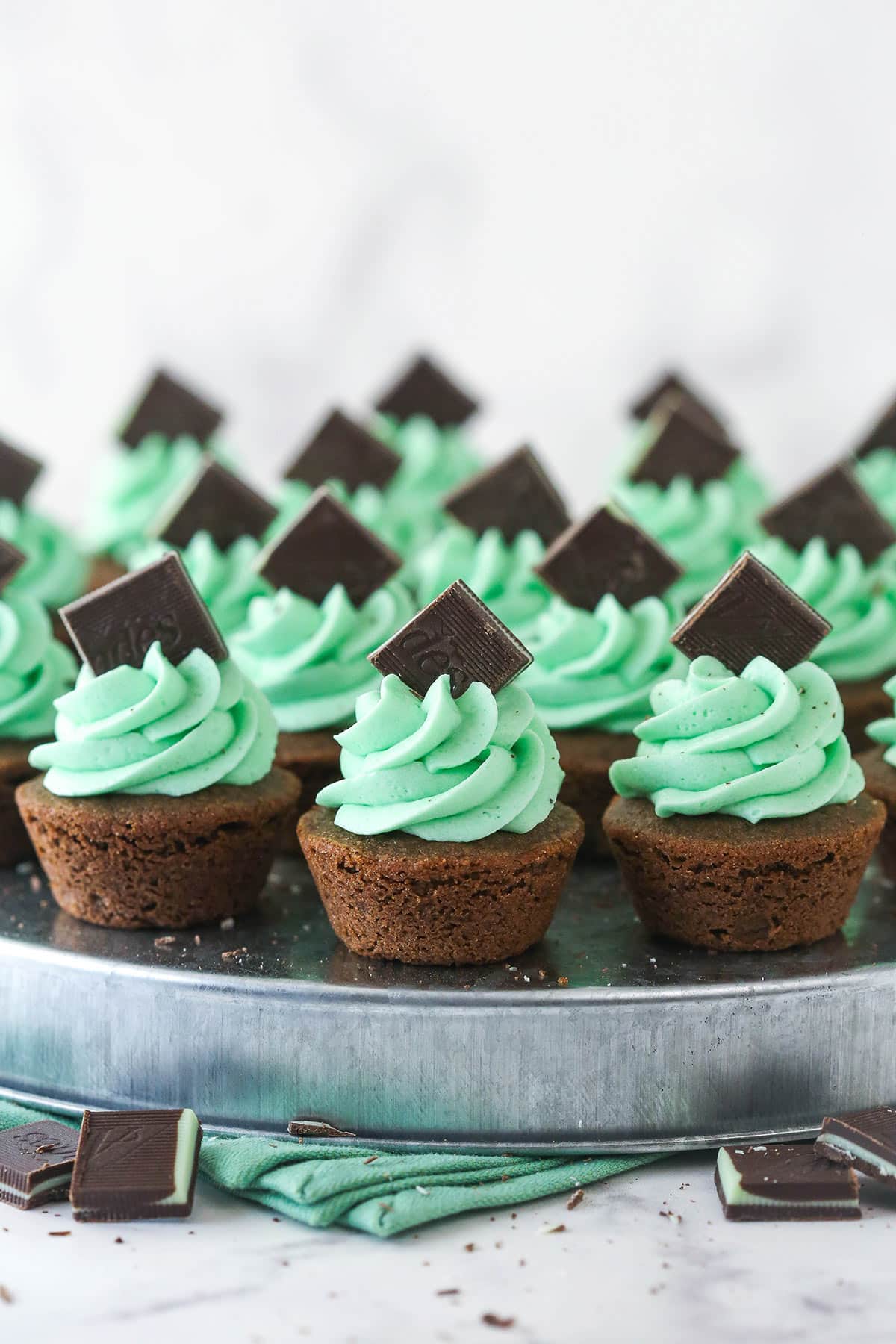 mint chocolate cookie cups frosted with mint buttercream and topped with Andes mint on a silver platter