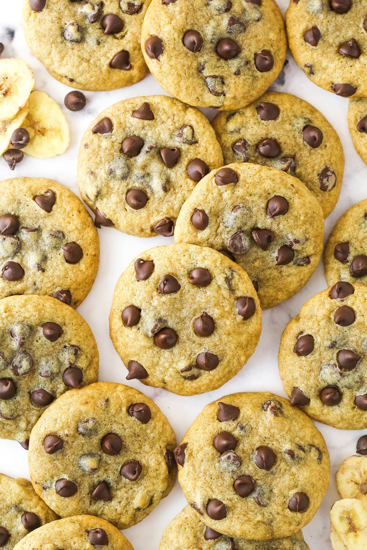 Overhead image of banana chocolate chip cookies scattered on a countertop.