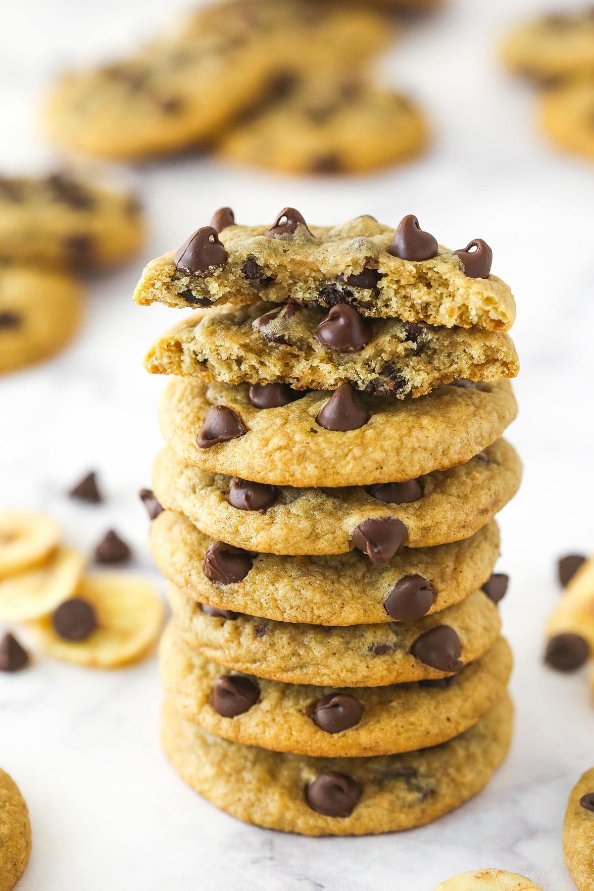 A stack of banana chocolate chip cookies. The top cookie is broken in half.