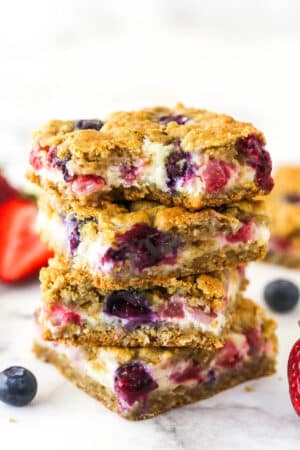 A stack of berry oatmeal cheesecake bars. The top one has a bite taken out of it.